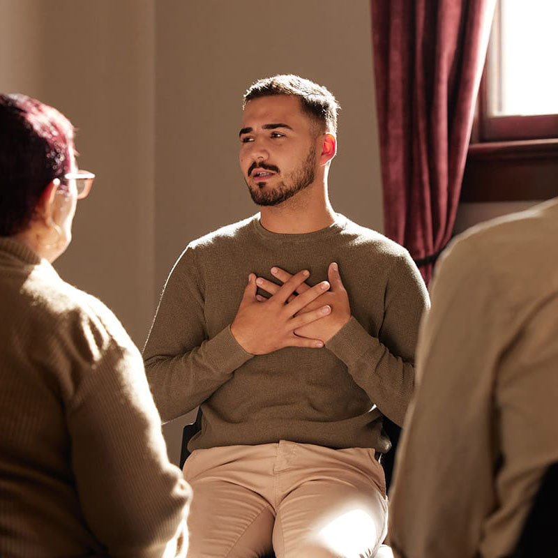 a person puts their hands on their chest to tell a story in outpatient addiction treatment