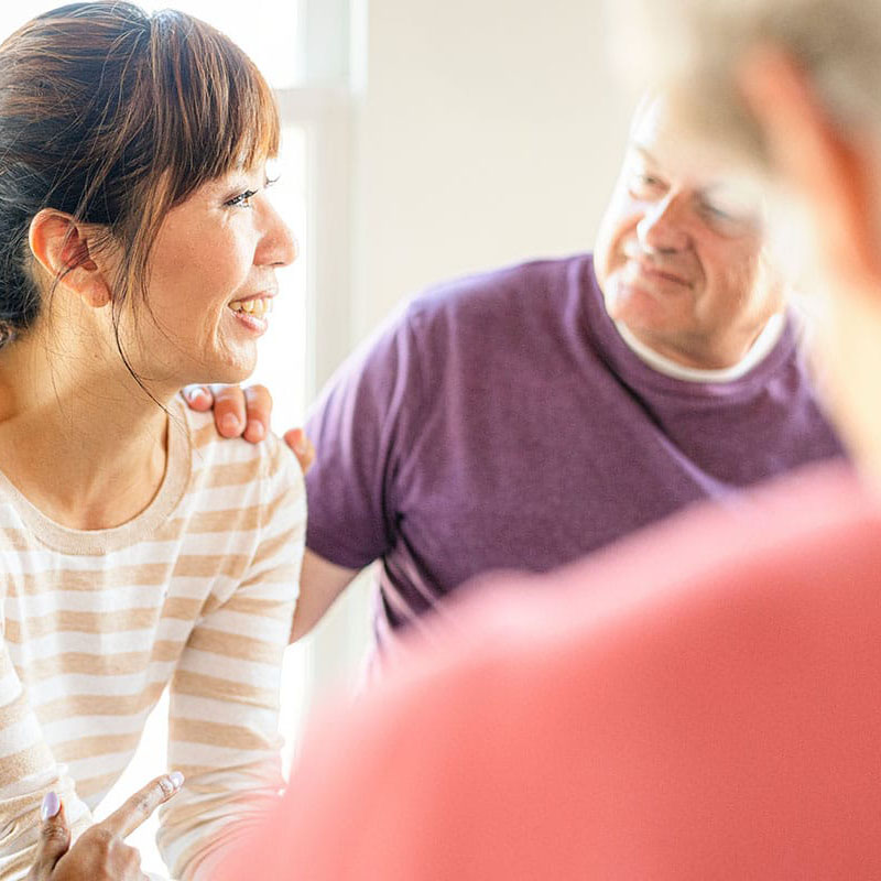 a person puts their hand on a smiling person's shoulder while in outpatient alcohol treatment