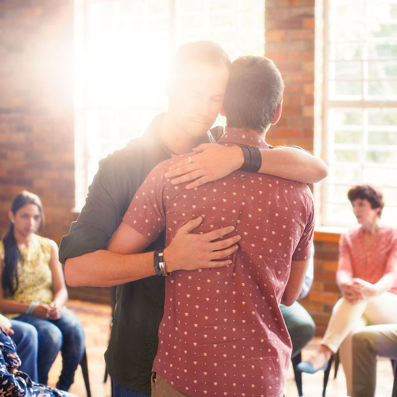 two people hug in group in an outpatient drug treatment program in Atlanta