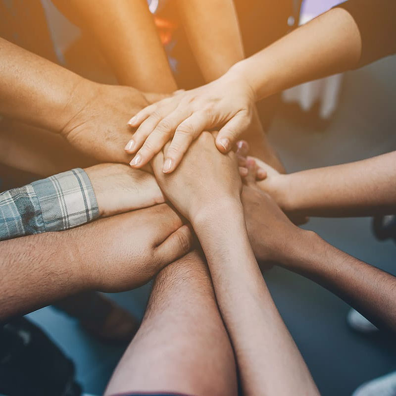 a group of people put their hands in the middle of a circle in a group therapy exercise for outpatient drug treatment near Atlanta