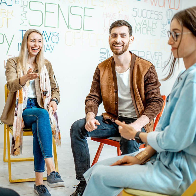 a group of people sit in chairs and talk in an outpatient mental health treatment program