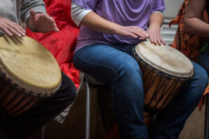 a group of people bang drums in a music therapy program